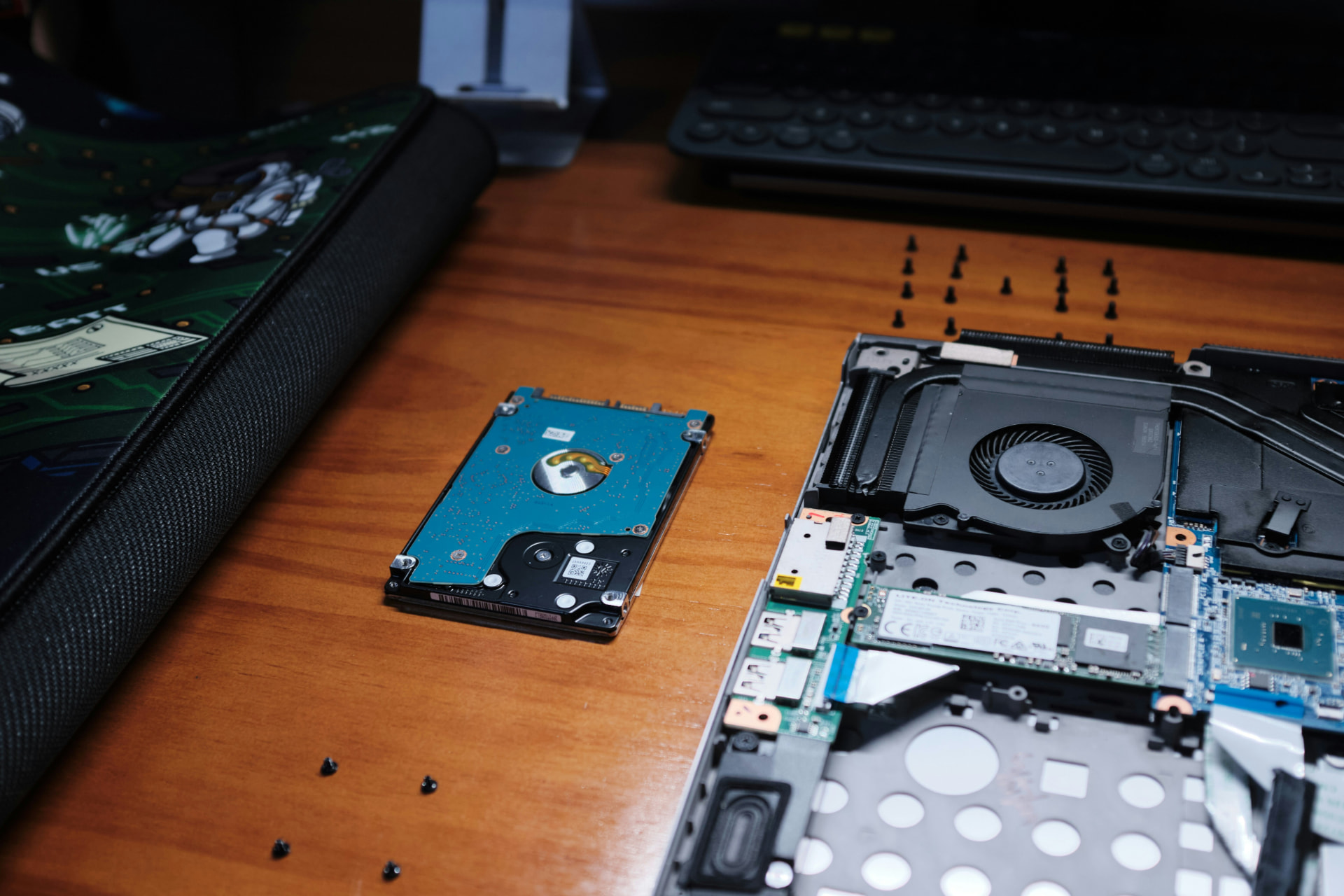 Open laptop beside a removed hard drive during a storage repair
