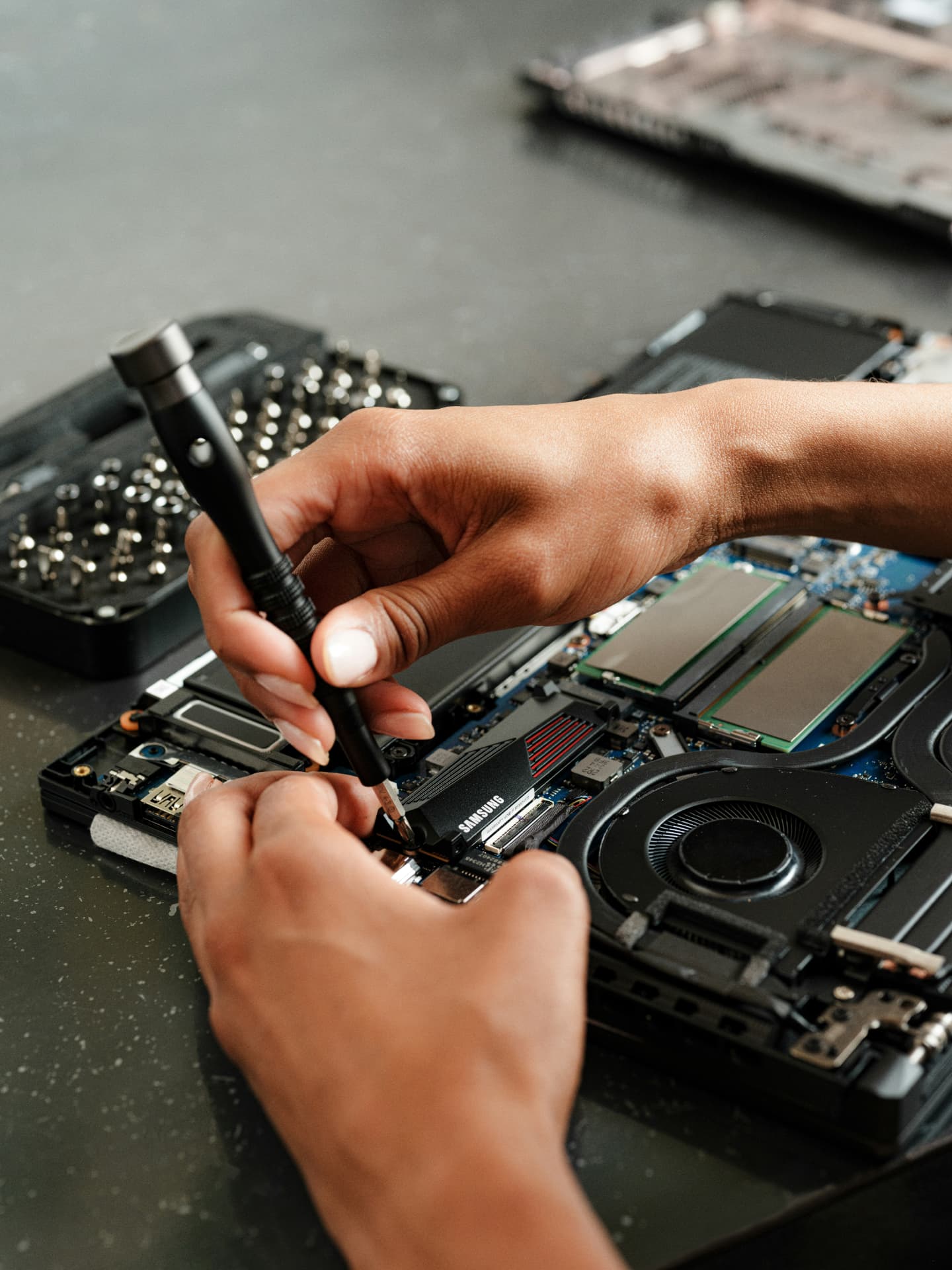 Technician installing a solid-state drive in an open laptop