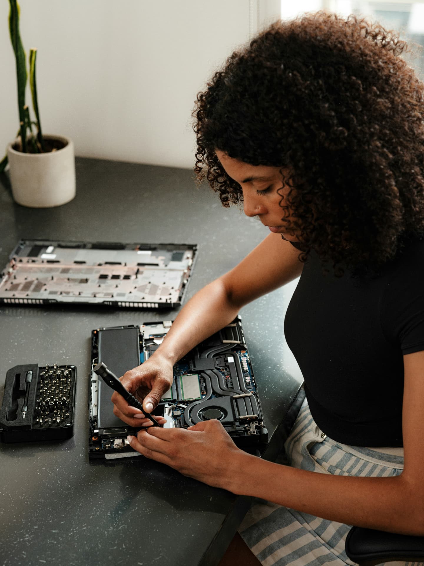 Technician carefully repairing an open laptop at a workbench