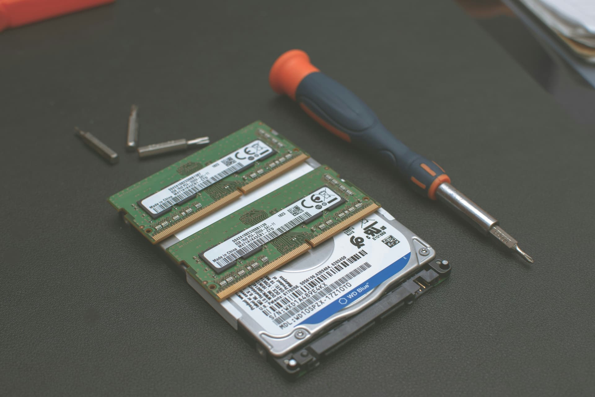 Laptop memory modules and hard drive arranged beside precision repair tools