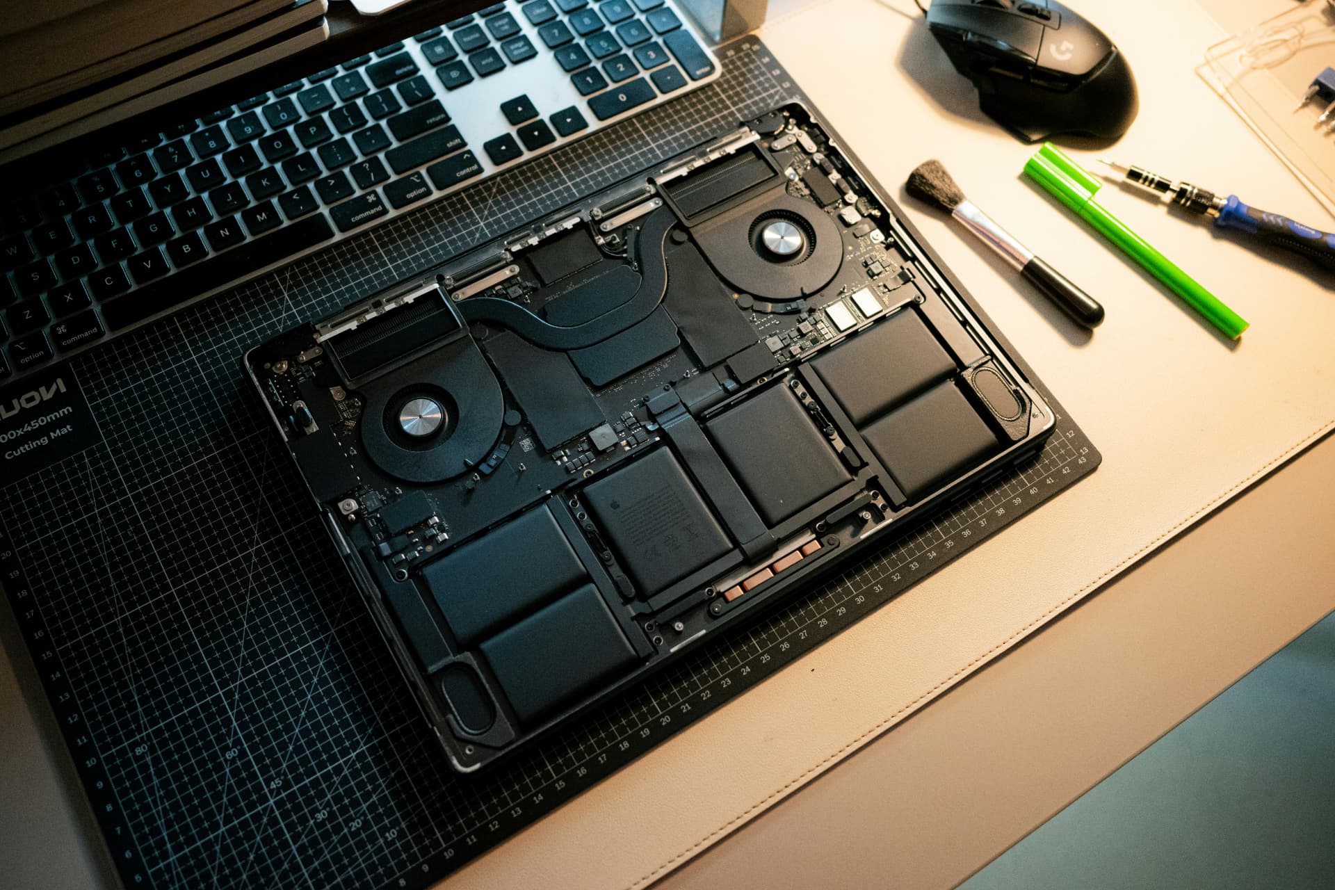 Open MacBook showing its battery, cooling fans and logic board